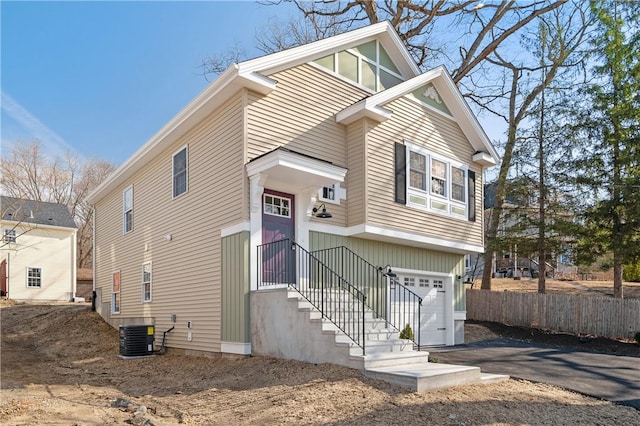 view of front of property with aphalt driveway, fence, a garage, and central AC