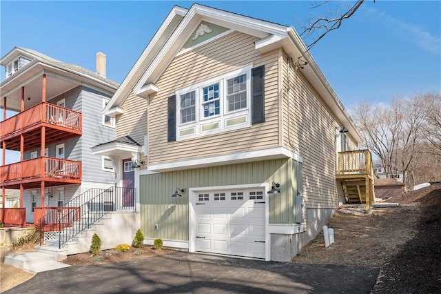 view of front of property featuring stairs, aphalt driveway, and an attached garage