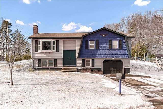 split foyer home featuring a gambrel roof, entry steps, a chimney, driveway, and an attached garage