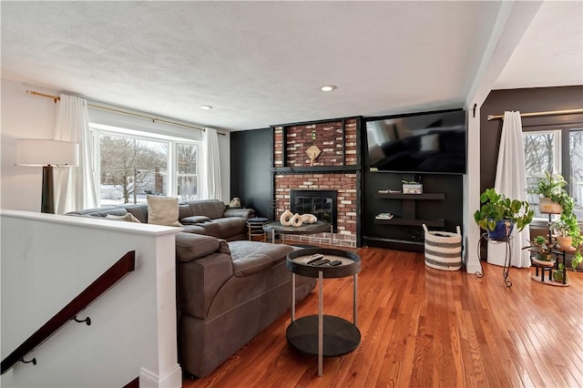 living room featuring a wealth of natural light, a fireplace, wood-type flooring, and a textured ceiling