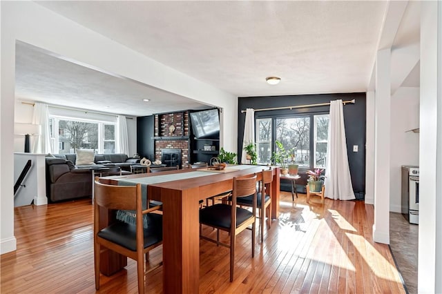 dining room featuring baseboards, plenty of natural light, light wood-style flooring, and a fireplace