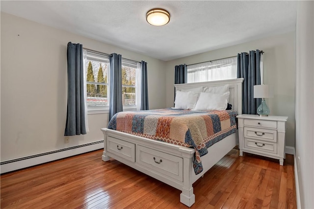 bedroom featuring light wood finished floors and baseboard heating