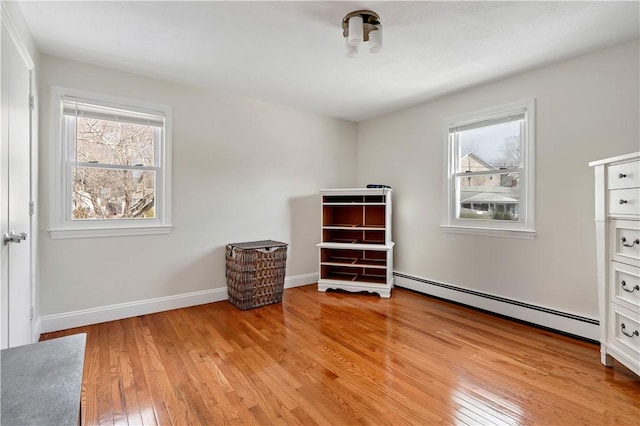 unfurnished bedroom featuring baseboards, light wood-type flooring, and a baseboard radiator