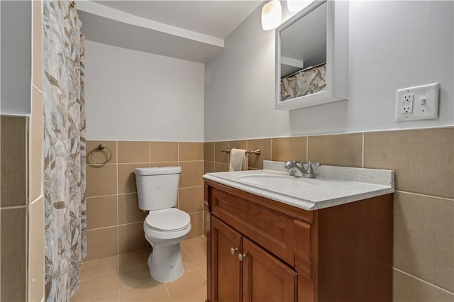 bathroom with vanity, a wainscoted wall, tile patterned flooring, tile walls, and toilet