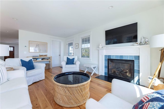 living area featuring a tiled fireplace, recessed lighting, and wood finished floors