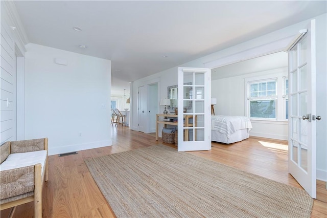 corridor featuring french doors, visible vents, light wood finished floors, and baseboards