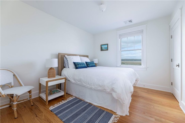 bedroom with baseboards, visible vents, and light wood-type flooring