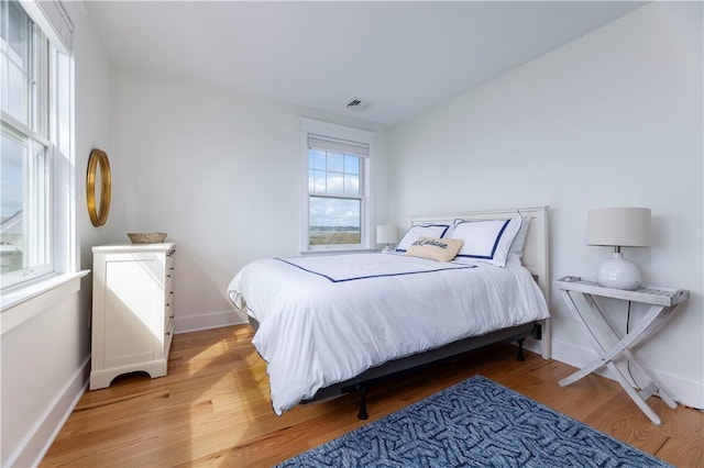 bedroom featuring visible vents, baseboards, and wood finished floors