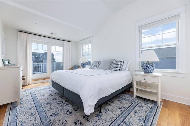 bedroom with visible vents, baseboards, vaulted ceiling, wood finished floors, and access to outside