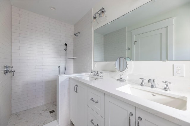 full bath with double vanity, a walk in shower, and a sink