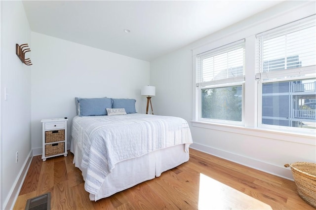 bedroom with visible vents, baseboards, and wood finished floors