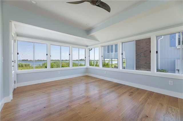 unfurnished sunroom featuring beamed ceiling, a healthy amount of sunlight, and a ceiling fan