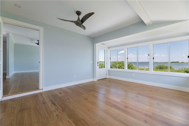 empty room with beamed ceiling, wood finished floors, baseboards, and ceiling fan