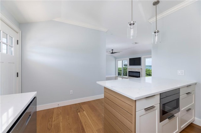 kitchen featuring stainless steel microwave, ceiling fan, decorative light fixtures, a fireplace, and light wood-style floors