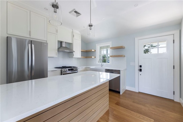 kitchen featuring visible vents, open shelves, a sink, stainless steel appliances, and wall chimney range hood