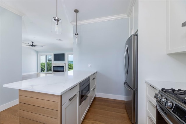 kitchen with a peninsula, stainless steel appliances, ceiling fan, and wood finished floors