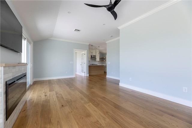 unfurnished living room featuring light wood-type flooring, ornamental molding, a fireplace, baseboards, and ceiling fan