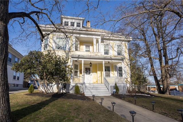 view of front of home with a chimney, a porch, and a front yard