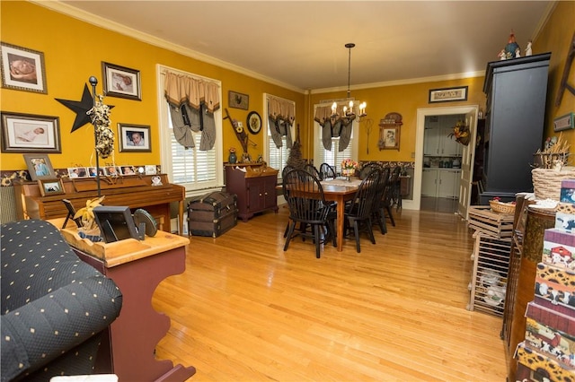 dining room featuring wood finished floors, a chandelier, and crown molding