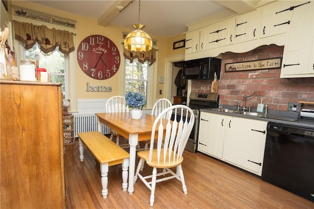 dining room featuring beam ceiling, a notable chandelier, radiator, and light wood finished floors