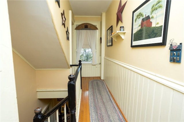 hall with crown molding, wood finished floors, and wainscoting