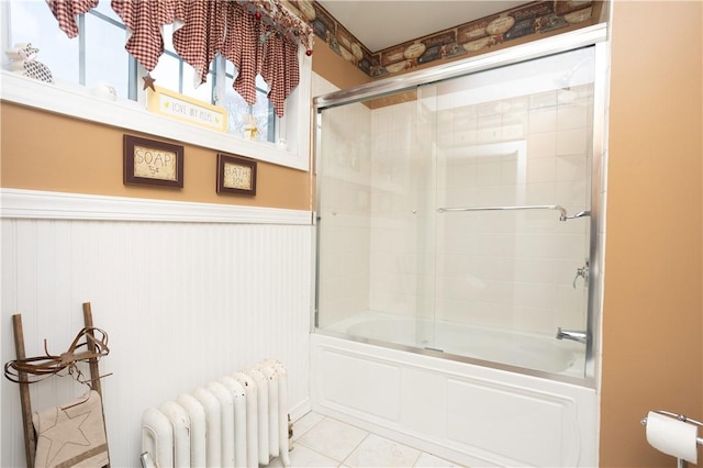 bathroom featuring bath / shower combo with glass door, wainscoting, radiator heating unit, and tile patterned flooring