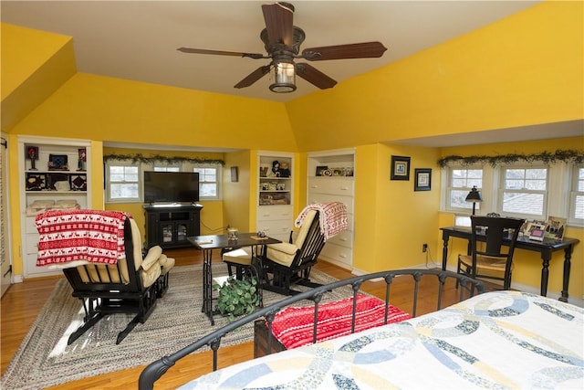 bedroom with vaulted ceiling, wood finished floors, and baseboards