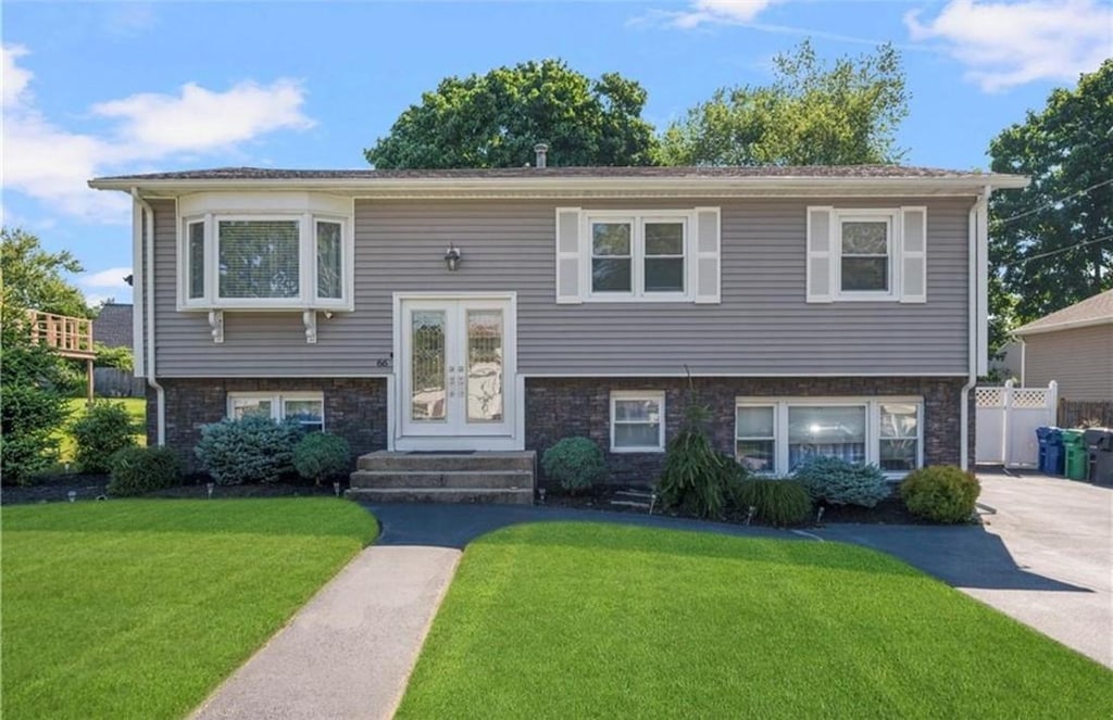 bi-level home featuring french doors, fence, and a front lawn