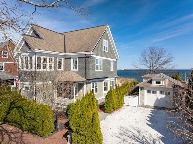 view of front of house with an outdoor structure, driveway, a shingled roof, and covered porch