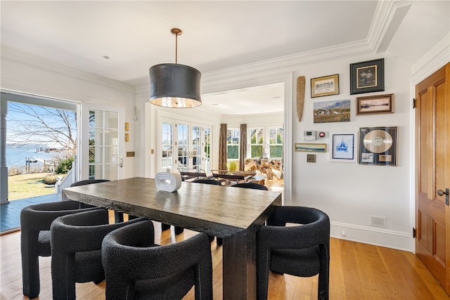 dining area featuring light wood-style floors, baseboards, and ornamental molding
