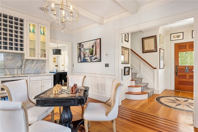 dining room featuring crown molding, stairs, an inviting chandelier, light wood-style flooring, and beam ceiling