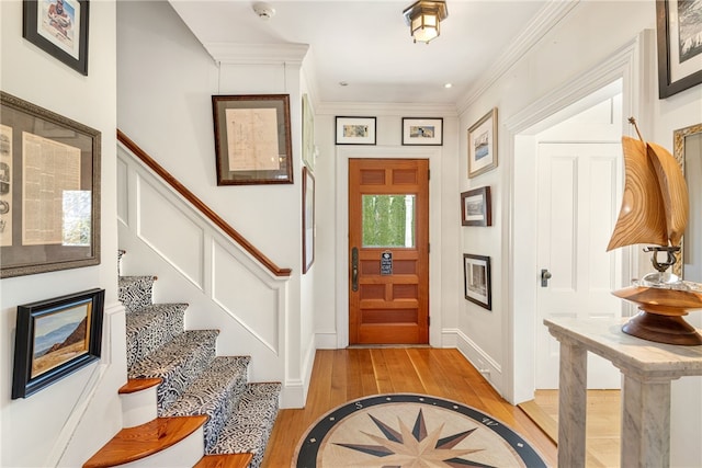 foyer entrance with baseboards, light wood-style flooring, stairs, and ornamental molding