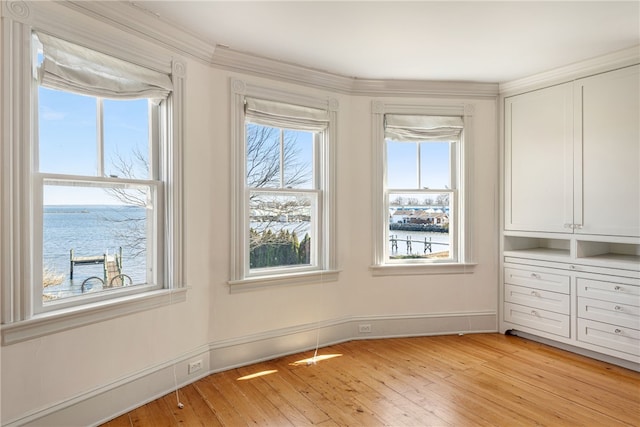 interior space featuring light wood-type flooring, baseboards, a water view, and multiple windows