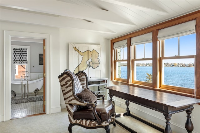 interior space featuring a water view, vaulted ceiling with beams, and light colored carpet
