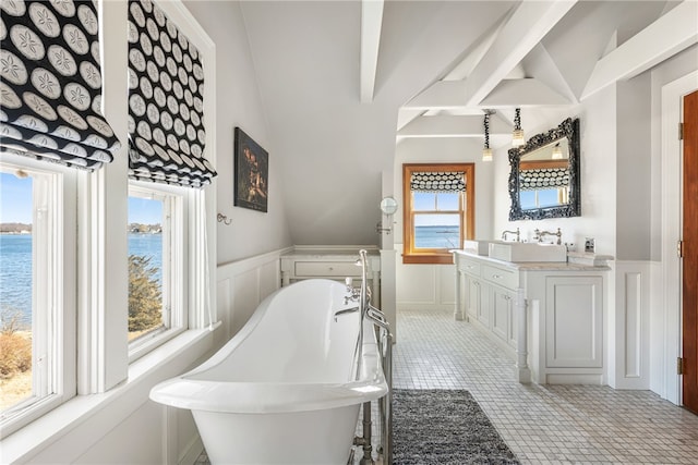 full bathroom with a wainscoted wall, a water view, vanity, a decorative wall, and a soaking tub