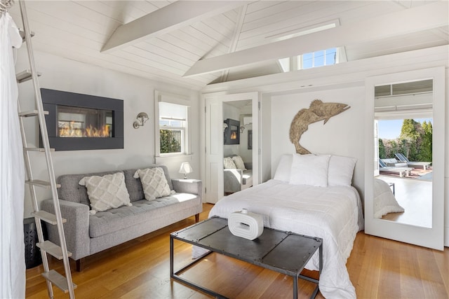 bedroom featuring vaulted ceiling with beams, hardwood / wood-style flooring, and multiple windows