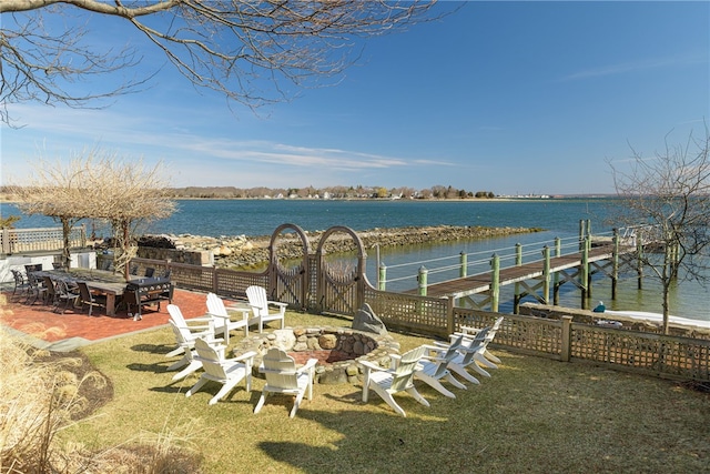 view of yard with a fire pit, fence, a water view, and a dock