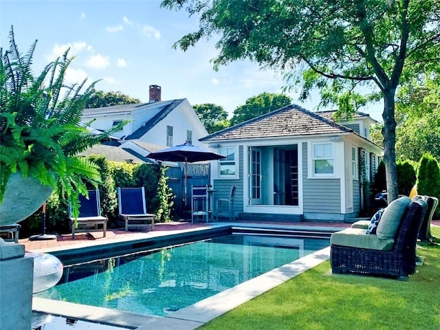 rear view of house featuring an exterior structure, a patio area, a lawn, an outdoor pool, and an outdoor structure