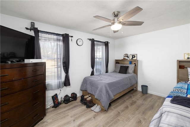 bedroom with baseboards, light wood-style flooring, ceiling fan, and a textured ceiling