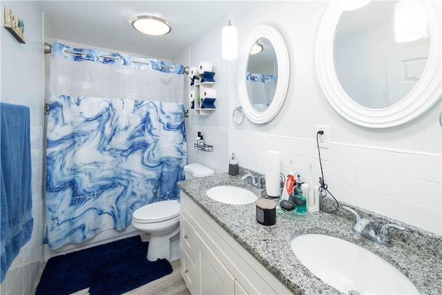full bathroom with tile walls, a sink, toilet, and a shower with shower curtain