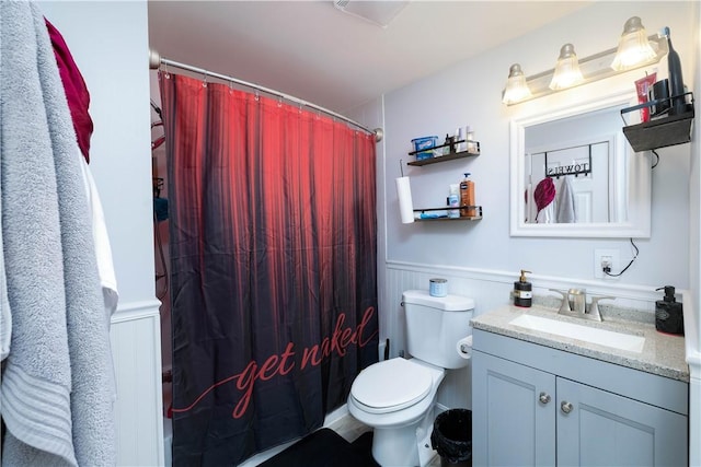 bathroom featuring a shower with curtain, wainscoting, toilet, and vanity