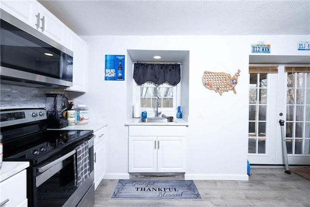 kitchen featuring light countertops, light wood-style flooring, a sink, and appliances with stainless steel finishes