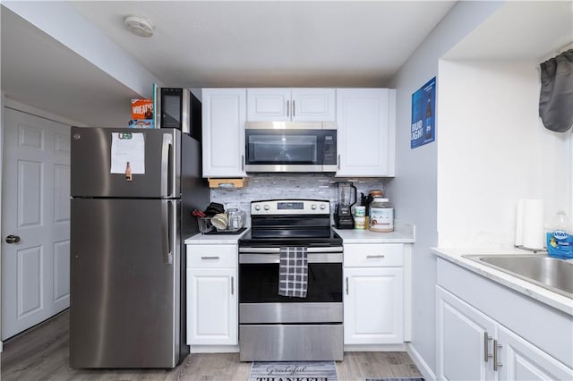 kitchen with white cabinetry, light countertops, stainless steel appliances, and decorative backsplash