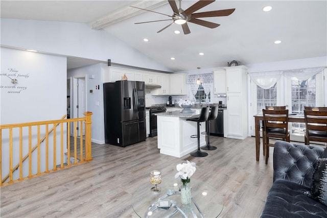 kitchen featuring white cabinetry, a kitchen bar, gas stove, refrigerator with ice dispenser, and a ceiling fan