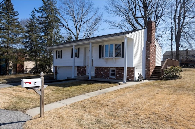 raised ranch featuring a garage, brick siding, a chimney, and a front lawn