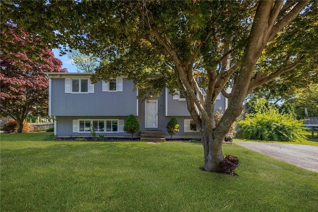 bi-level home featuring fence, a front yard, and entry steps