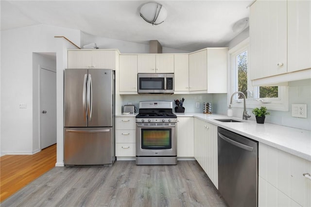 kitchen with tasteful backsplash, stainless steel appliances, light countertops, and a sink