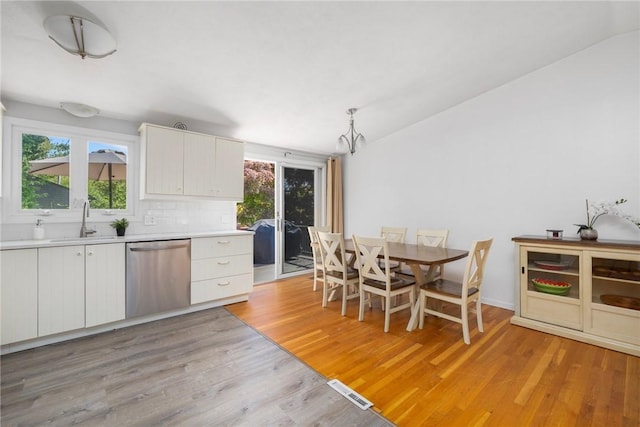 kitchen featuring a sink, light wood-type flooring, dishwasher, and light countertops