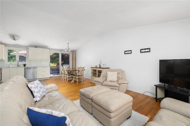 living area with baseboards, lofted ceiling, and light wood-style flooring