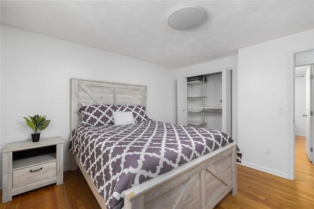 bedroom with a closet, baseboards, and wood finished floors